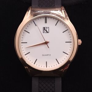 K brand medium size gold-tone quartz movement watch with a black rubber strap.